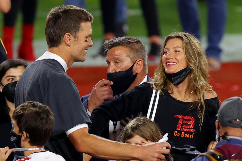 A beautiful man and a beautiful woman move toward each other amid a crowd on a football field