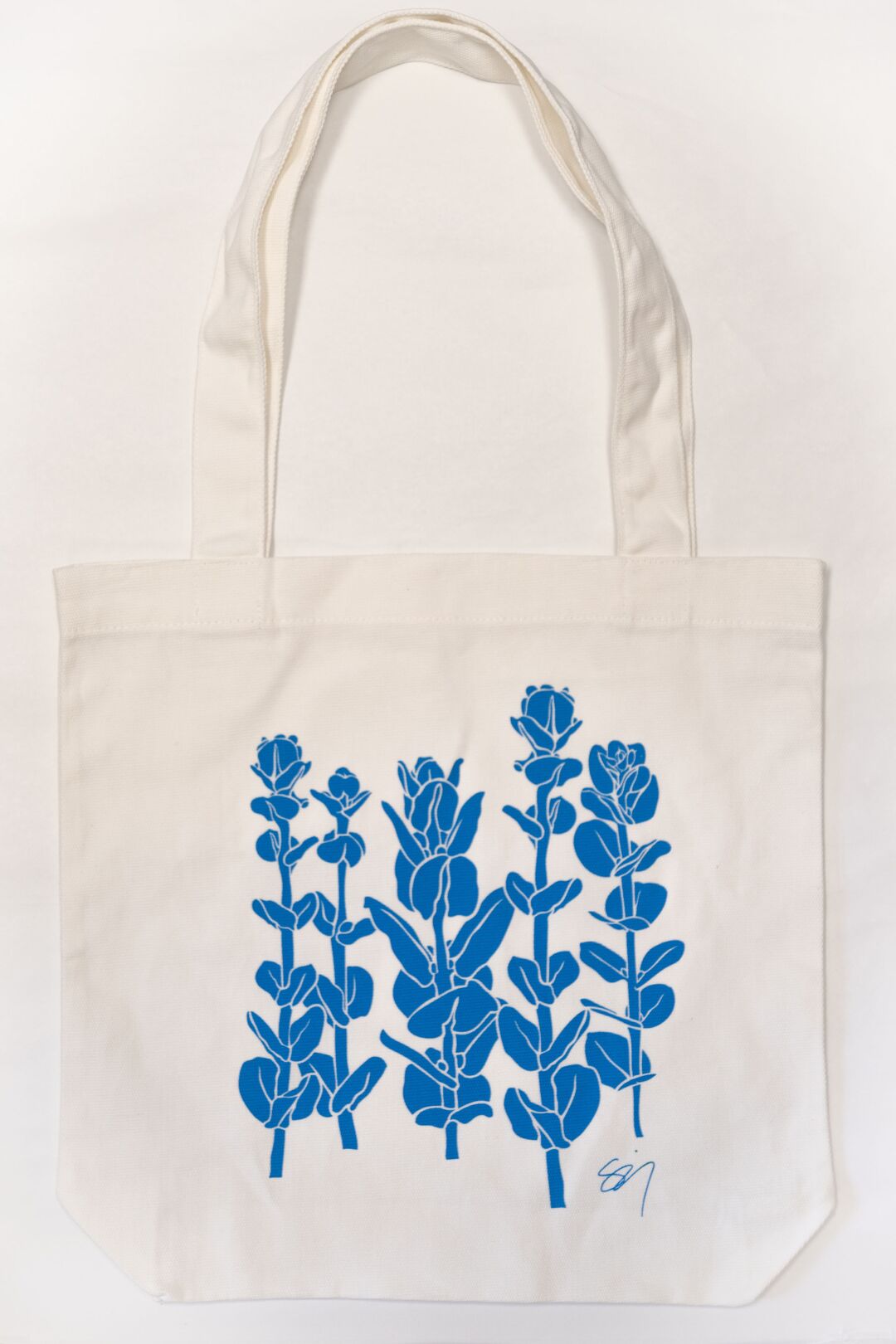 A white tote bag decorated with blue flowers