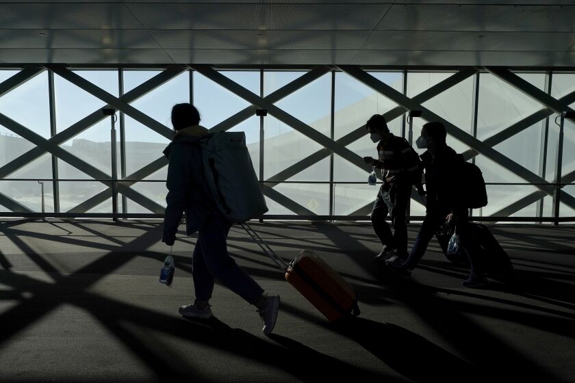 Travelers drag luggage while walking out of a terminal at San Francisco International Airport