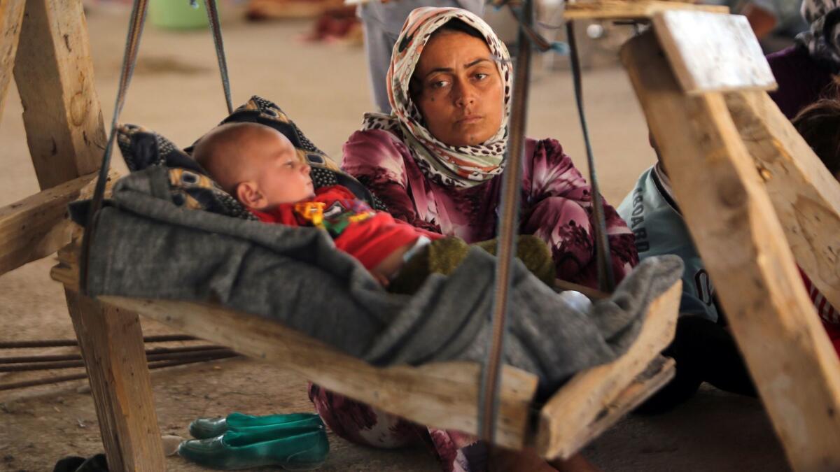 An Iraqi Yazidi woman, who fled her home when Islamic State militants attacked the town of Sinjar, looks at her baby as they rest inside a building under construction where they sought refuge on the outskirts of the Kurdish city of Dahuk, in August, 2014.
