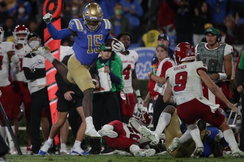 PASADENA, CA - SEPTEMBER 18, 2021: UCLA Bruins linebacker Jordan Genmark Heath (15) leaps over Fresno State defense after recovering a fumble in the 4th quarter at the Rose Bowl on September 18, 2021 in Pasadena, California.(Gina Ferazzi / Los Angeles Times)