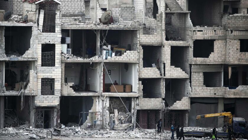 Syrians walk past a destroyed building in Arbin in the rebel-held enclave of eastern Ghouta on Feb. 25, 2018.