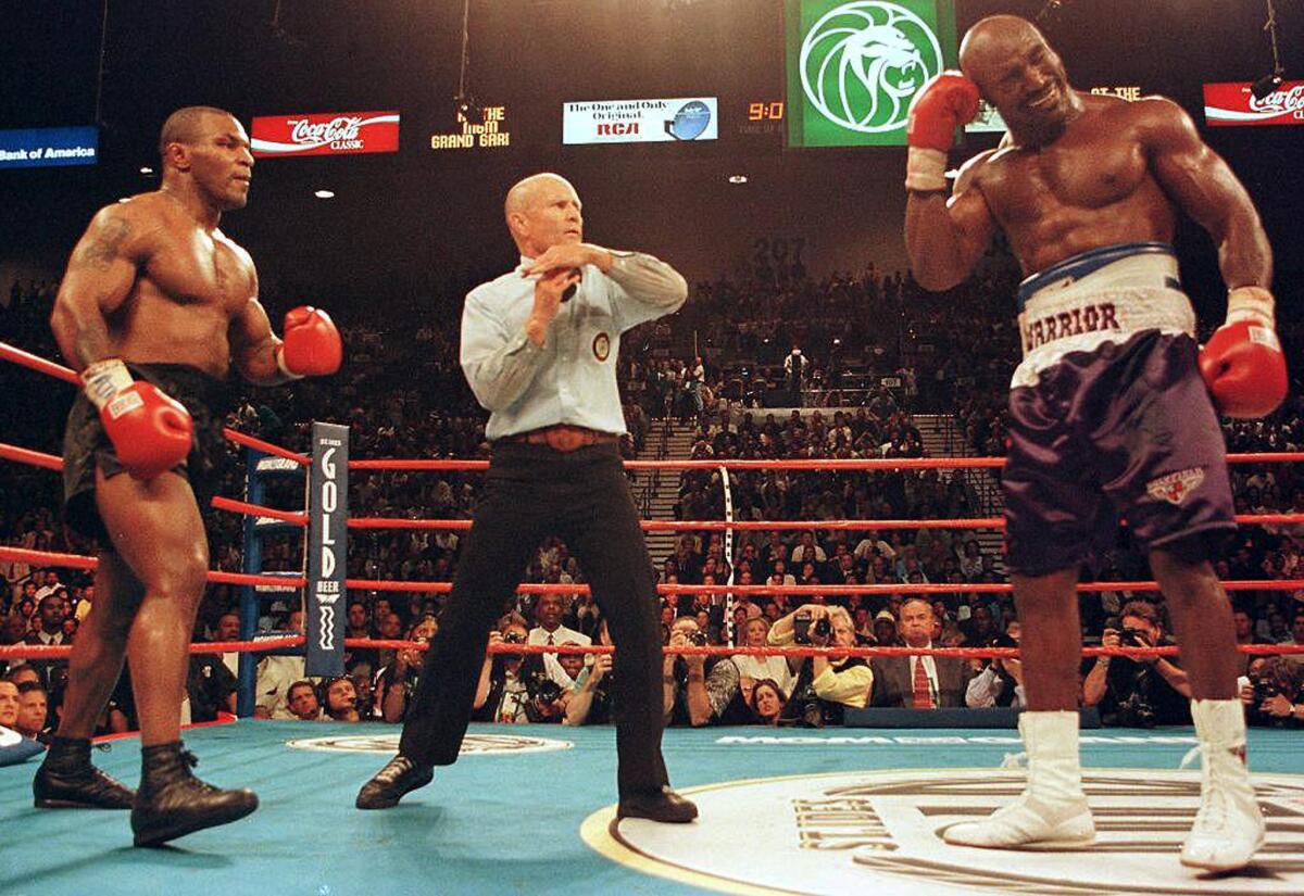 Referee Lane Mills stops the fight in the third round as Evander Holyfield holds his ear after being bitten by Mike Tyson, left, during their heavyweight title fight in June 1997.