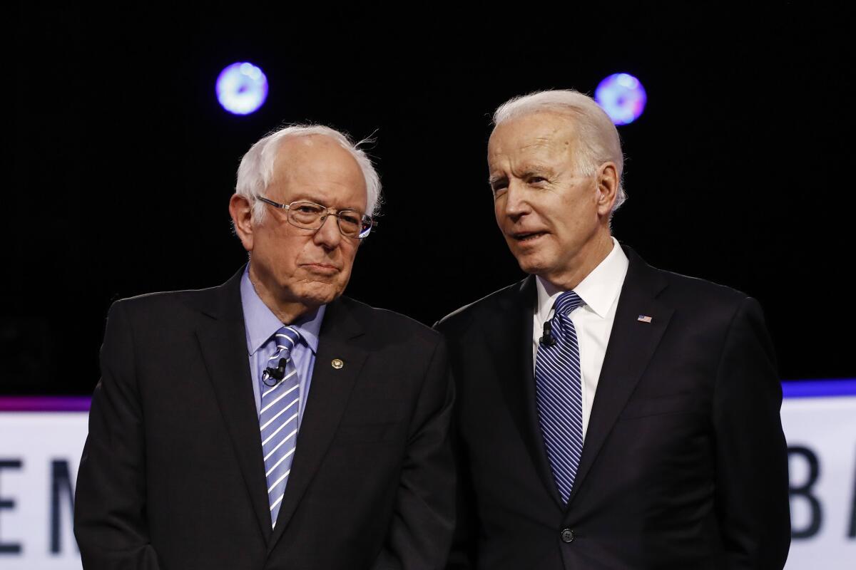 Democratic presidential candidates Sen. Bernie Sanders and former Vice President Joe Biden talk before a debate in Charleston, S.C., on Feb. 25.