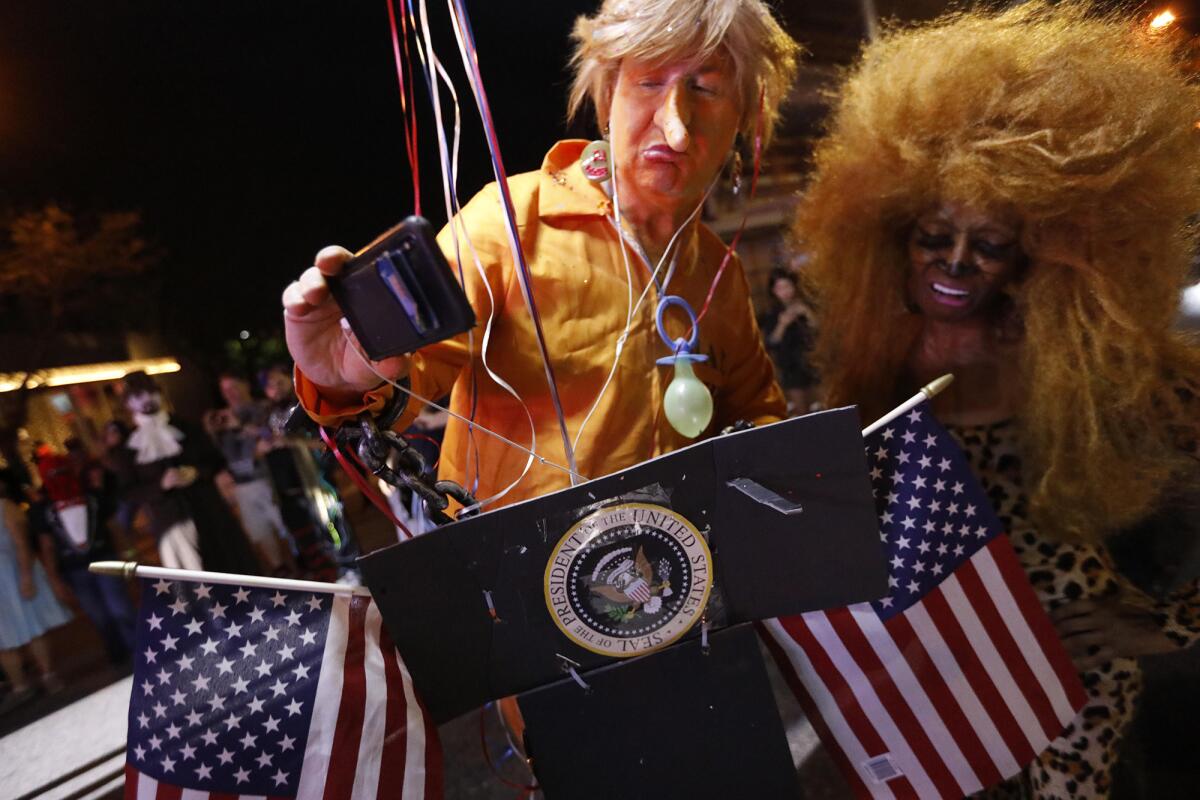 Thomas O'Malley, as President Trump, takes a selfie from his motorized podium with Dolly Boyd at the Halloween Carnaval.
