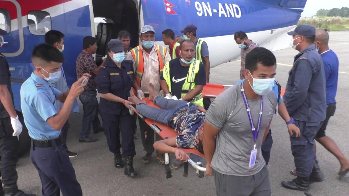 One among many passengers injured in a bus accident in western Nepal's Mugu district is rushed for treatment after being airlifted to Nepalgunj, Nepal, Tuesday, Oct.12, 2021. Several people died after a bus they were on skidded off a mountain road and fell hundreds of yards into a gorge. (AP Photo/ Krishna Adhikari )