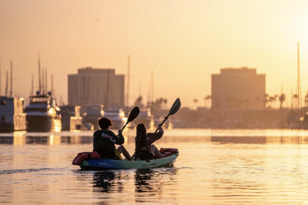 Kayakers paddles in a double kayak as the sun sets. 