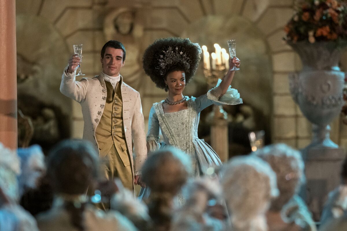 Young King George and young Queen Charlotte raising their glasses to a crowd.