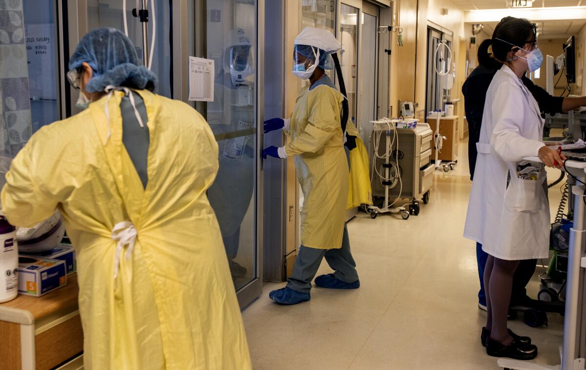  An ICU nurse wearing head-to-toe personal protective gear enters a room to treat a COVID-19 patient