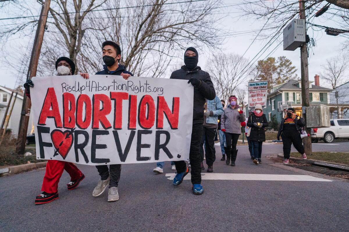 Activists hold a sign saying "Abortion Forever" and "RiseUp4AbortionRights.org"