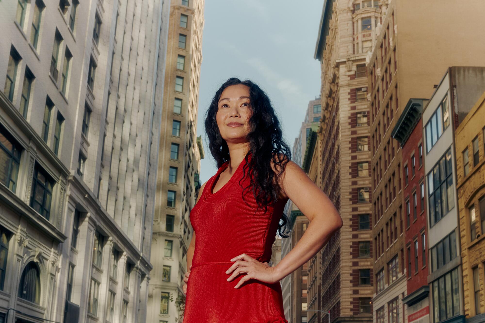Hong Chau stands in a New York City street in a red dress for a portrait.