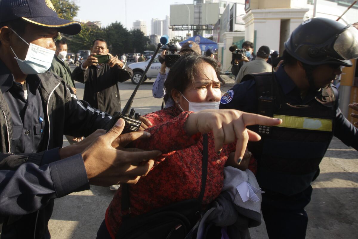 Prum Chenda, center, wife of a jailed former opposition activist, is stopped by security personnel as she tries to reach the Phnom Penh Municipal Court in Phnom Penh, Cambodia, Thursday, Jan. 14, 2021. The trial of more than 60 critics and opponents of the Cambodian government charged with treason and other offenses for taking part in nonviolent political activities resumed Thursday, with rights advocates skeptical that justice is being served. (AP Photo/Heng Sinith)