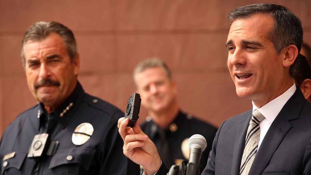 Mayor Eric Garcetti, right, shows off a police body camera at a 2015 news conference with LAPD Chief Charlie Beck. Thousands of L.A. police officers now wear the devices.