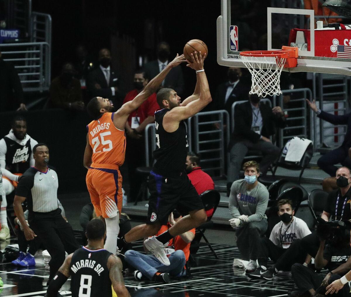 Mikal Bridges reaches over the head of Nicolas Batum as Batum prepares to shoot a basket.