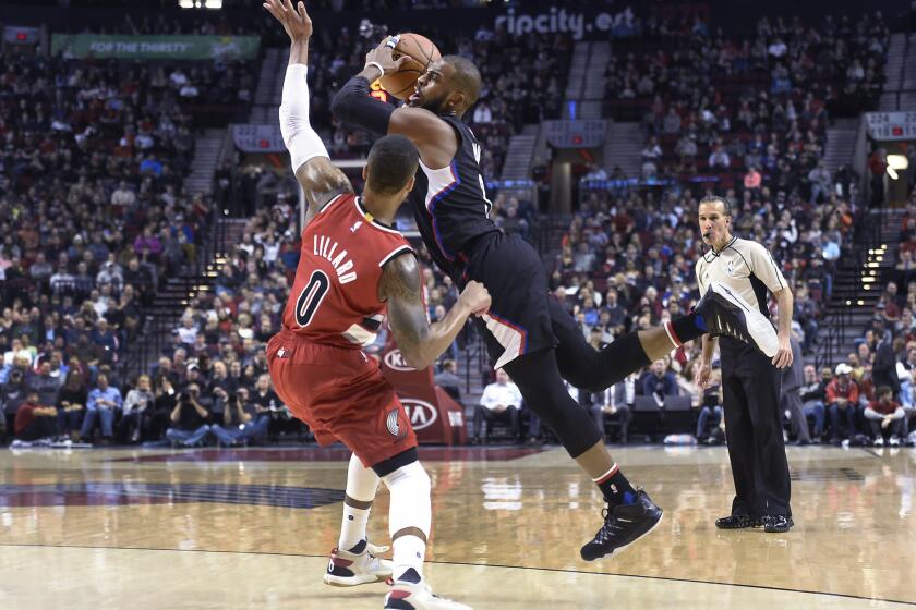 Trail Blazers guard Damian Lillard (0) fouls Clippers point guard Chris Paul (3) as he goes up for a shot during the first half.