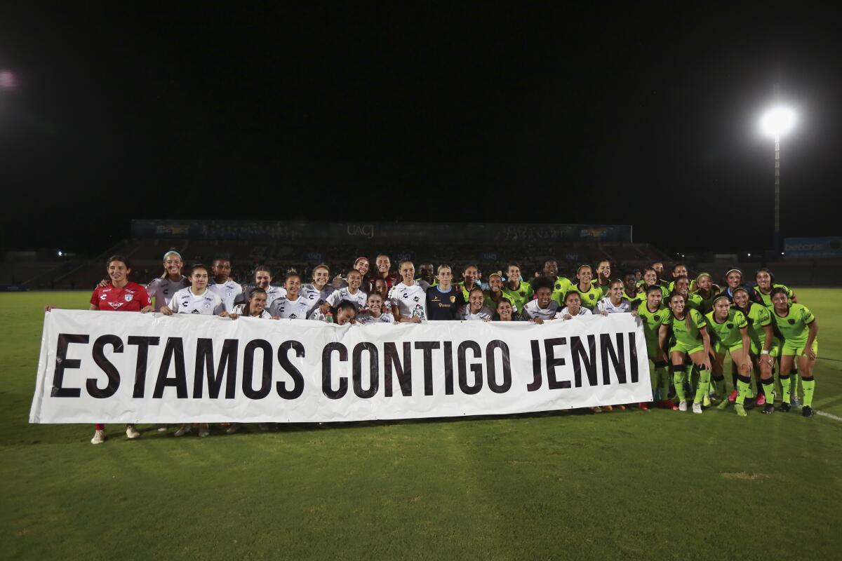 Jugadoras del Club Femenino Pachuca levantan una pancarta escrita en español, "Estamos contigo jenny"