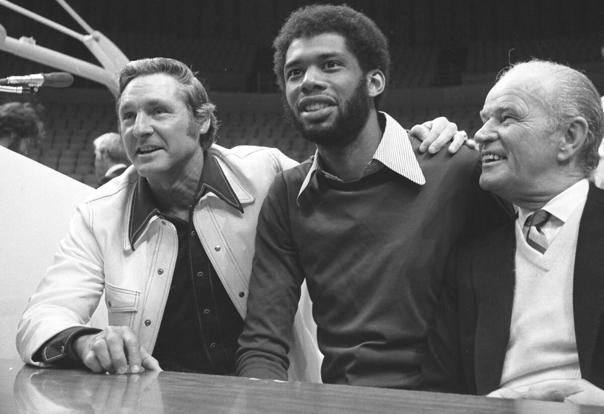 The men seated closely together at a table smile for a photo.