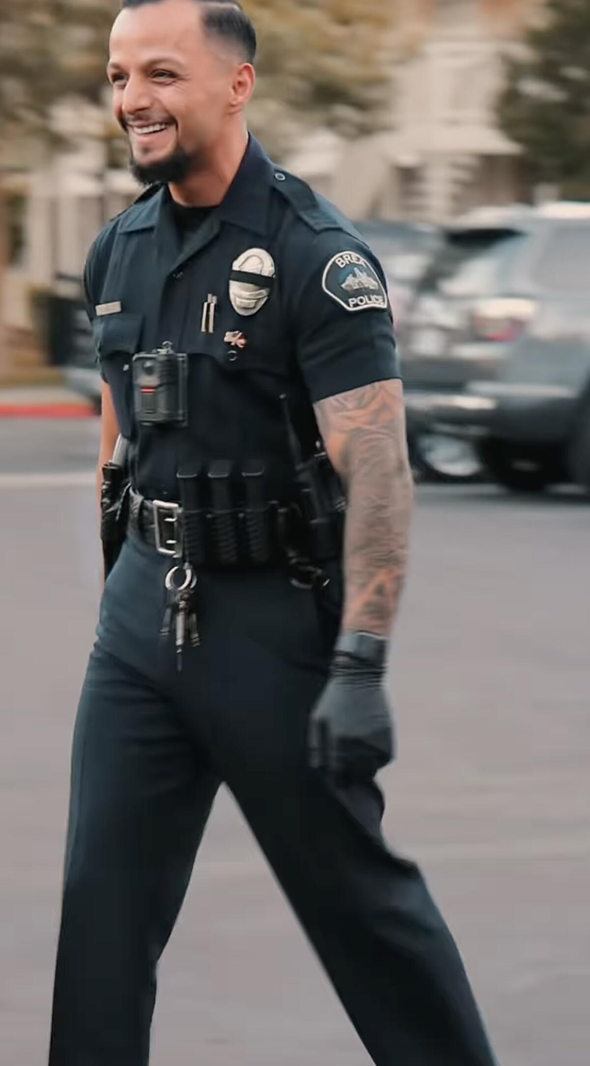 A police officer with visible tattoos on his left arm. 