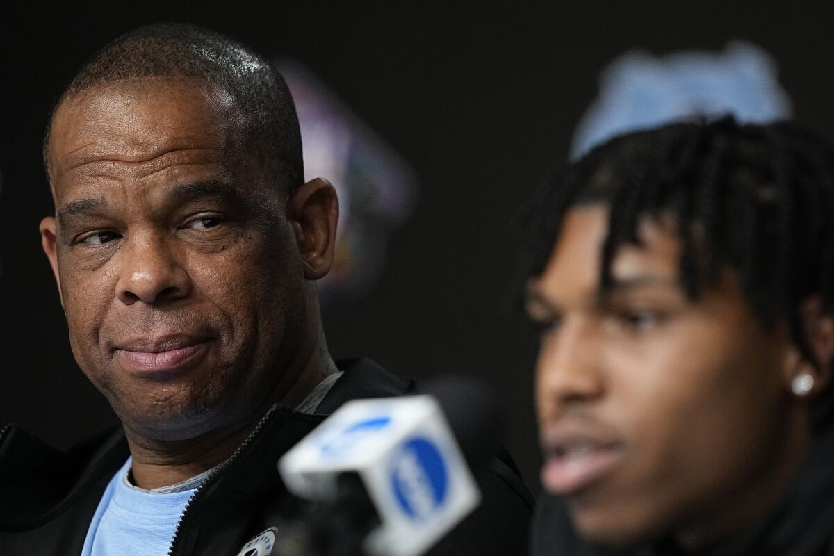 North Carolina head coach Hubert Davis, left, watches as guard Caleb Love speaks during a news conference about the Men's Final Four NCAA basketball tournament, Sunday, April 3, 2022, in New Orleans. North Carolina will face Kansas in the final game on Monday. (AP Photo/Brynn Anderson)
