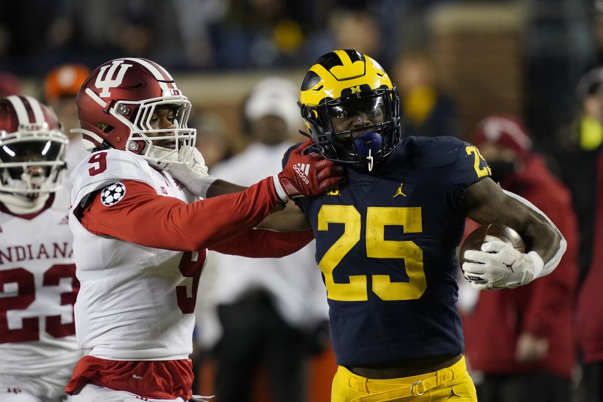 Michigan running back Hassan Haskins (25) is pushed out of bounds by Indiana defensive back Marcelino McCrary-Ball (9) after a 62-yard rush during the first half of an NCAA college football game against Indiana, Saturday, Nov. 6, 2021, in Ann Arbor, Mich. (AP Photo/Carlos Osorio)