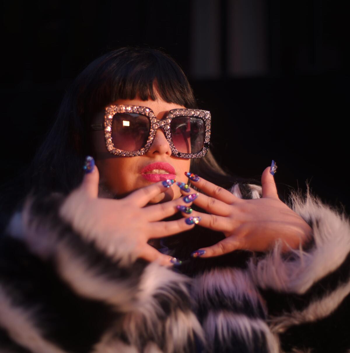 A young woman in bling'd out shades shows of her manicure
