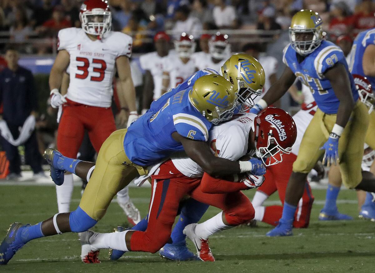 UCLA defenders Adarius Pickett (6) and Krys Barnes bring down Fresno State wide receiver Justin Allen in the second quarter on Sept. 15, 2018, at the Rose Bowl.