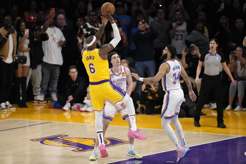 Los Angeles Lakers forward LeBron James, left, scores to pass Kareem Abdul-Jabbar to become the NBA's all-time leading scorer as Oklahoma City Thunder guard Josh Giddey, center, and forward Kenrich Williams defend during the second half of an NBA basketball game Tuesday, Feb. 7, 2023, in Los Angeles. (AP Photo/Mark J. Terrill)