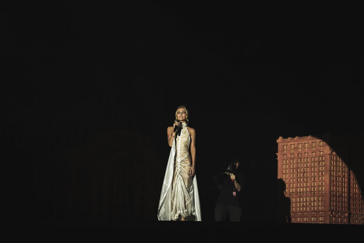 A blond woman in a white dress onstage