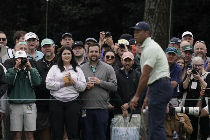 Spectators watch Tiger Woods on the driving range during a practice round for the Masters golf tournament on Tuesday, April 5, 2022, in Augusta, Ga. (AP Photo/Charlie Riedel)
