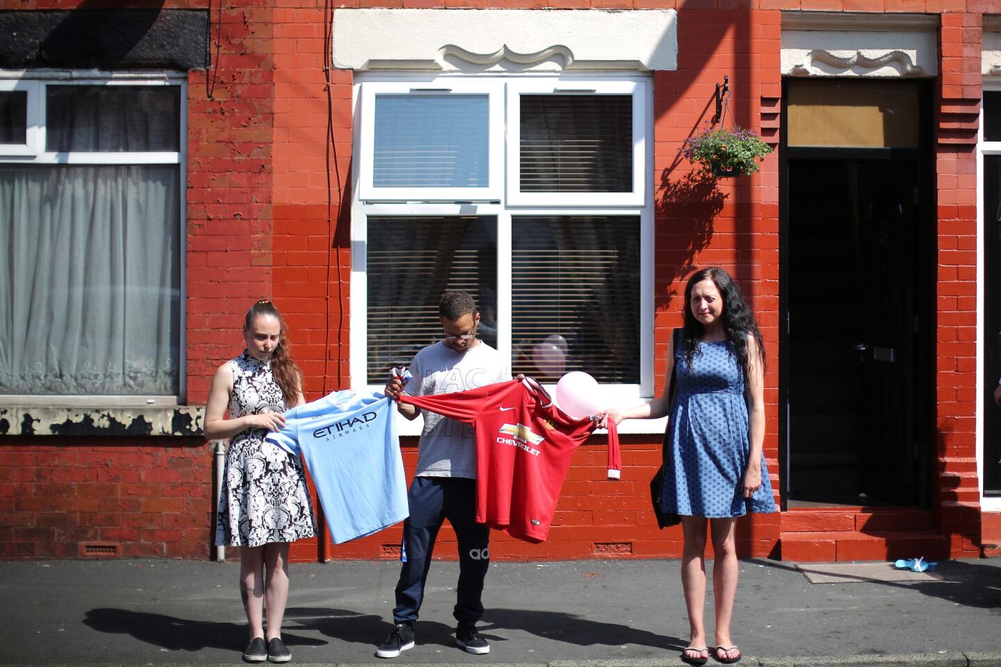 Residents of Lindum Street in Manchester observe a nationwide minute of silence while holding the jerseys of both famed Manchester soccer teams, Manchester City and Manchester United, in memory of the victims of the bomb attack on May 25, 2017.