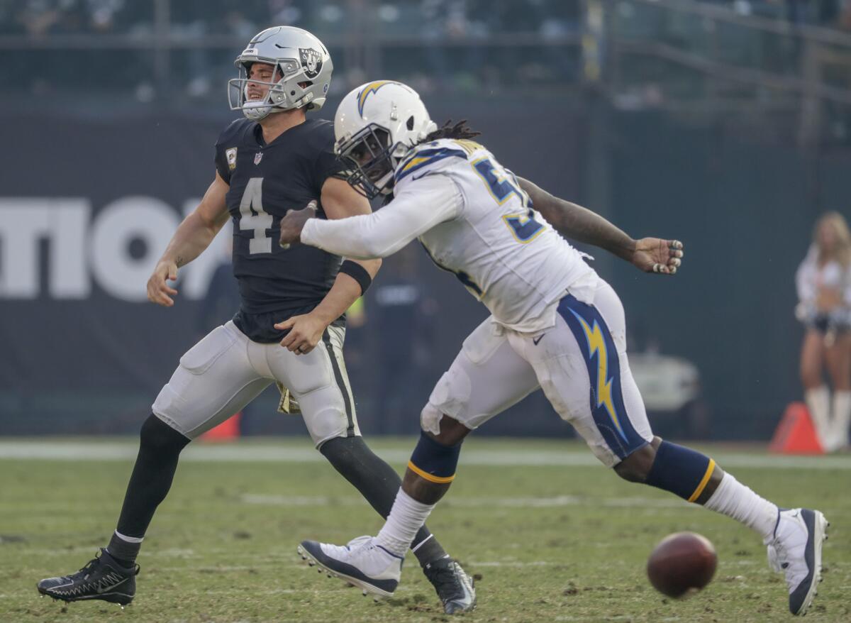 The Raiders' Derek Carr throws the ball to the ground to avoid a sack by Chargers linebacker Melvin Ingram III on a fourth down late in the game at Oakland-Alameda County Coliseum on Nov. 11.