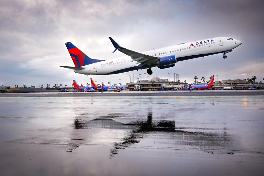 A Delta Airlines Boeing 737 is reflected in water along the side of the runway while taking off from San Diego International Airport, on February 5, a cold, and rainy day in San Diego.