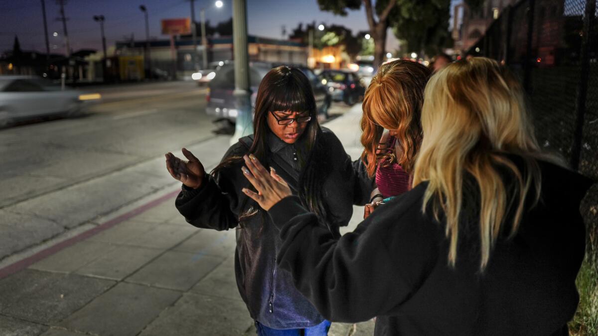 Members of Victory Outreach church Tamika Bonner, left, and Toni Dominguez, right, pray with with a woman on International Boulevard in Oakland. The church group helps women working as prostitutes with shelter and other social services.