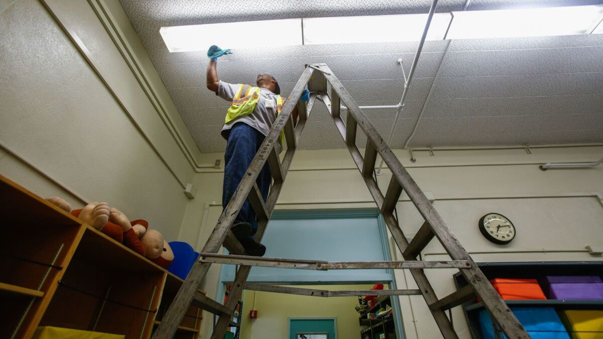 The L.A. school board acted Tuesday to maintain the current level of healthcare spending for district employees. Above, maintenance worker Johnny Bowie is shown working at 49th Street Elementary last August.
