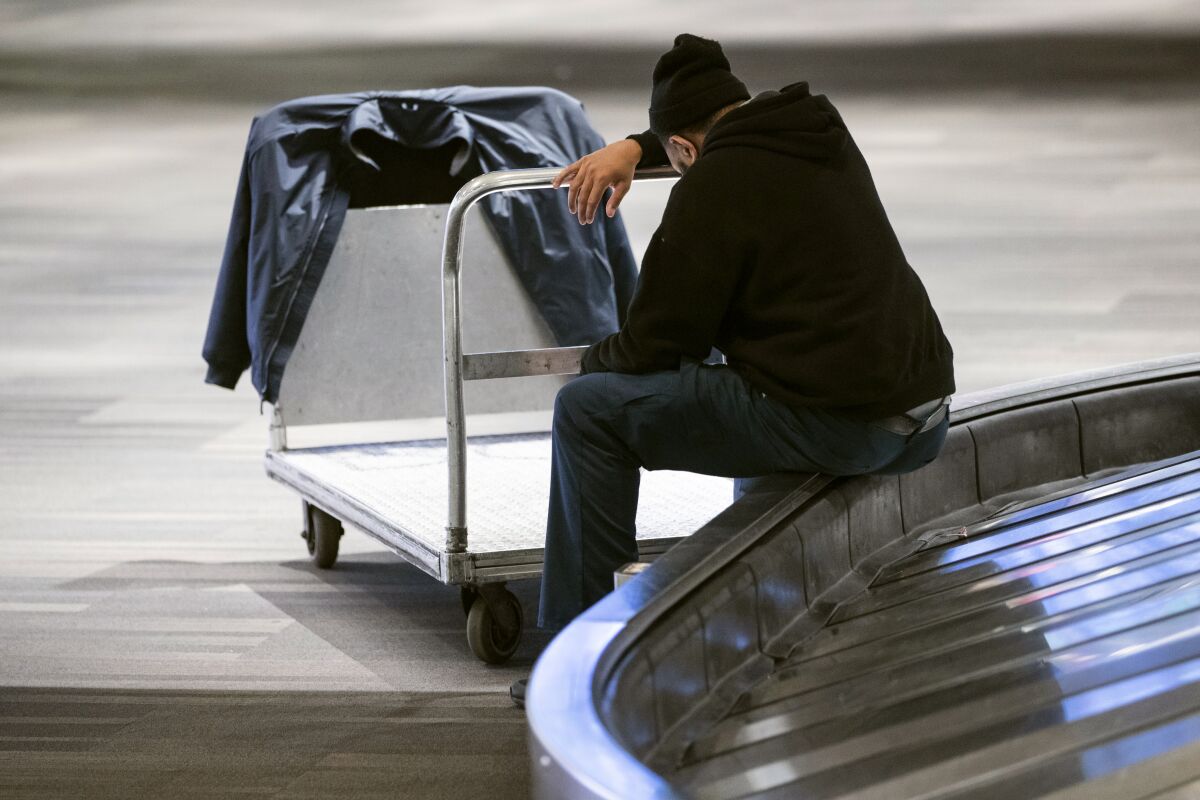 Baggage handler Mikal Hanton rests his head as he sits on a carousel last week at Philadelphia International Airport, where coronavirus-related layoffs are mounting.