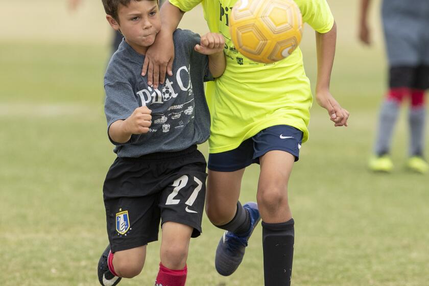 Newport Heights's Magnus Warmsley battles for a ball with Newport Beach Coast Elementary's Kavi Odabaee in a boysÕ third- and fourth-grade Bronze Division quarterfinal match at the Daily Pilot Cup on Saturday, June 1.