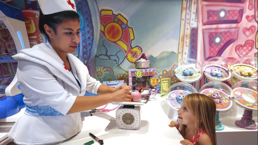 Nurse Tania, a.k.a. Danielle Hernandez, weighs and examines Susiking, one of the babies from the planet Neonatopia, at the Distroller World store in San Diego, as 4-year-old Sydney Stephens looks on.