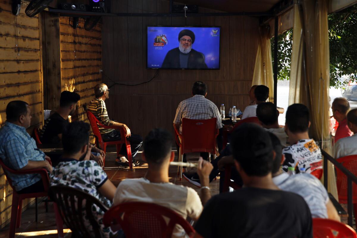 People listen to a speech by Hezbollah leader Sayyed Hassan Nasrallah being broadcast on Hezbollah's al-Manar TV channel, at a coffee shop in a southern suburb of Beirut, Lebanon, Sunday Aug. 25, 2019. Nasrallah said Hezbollah will confront and shoot down Israeli drones that fly over Lebanon from now on. (AP Photo/Bilal Hussein)