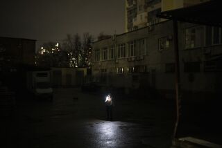 Una mujer utiliza su celular para iluminar el camino, en Kiev, Ucrania, el 31 de enero de 2023. (AP Foto/Daniel Cole)