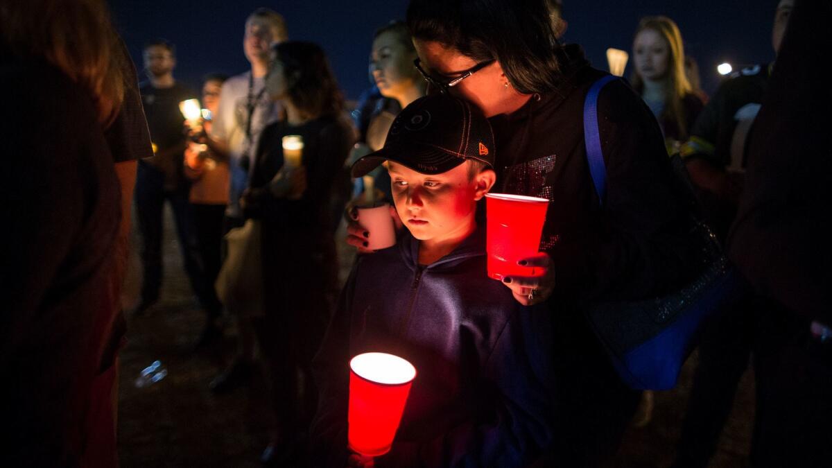 Keli McDade of Las Vegas leans on her son Ayden during a candlelight vigil at Town Square in Las Vegas in tribute to those killed and injured after a gunman opened fire on the Route 91 Harvest festival.