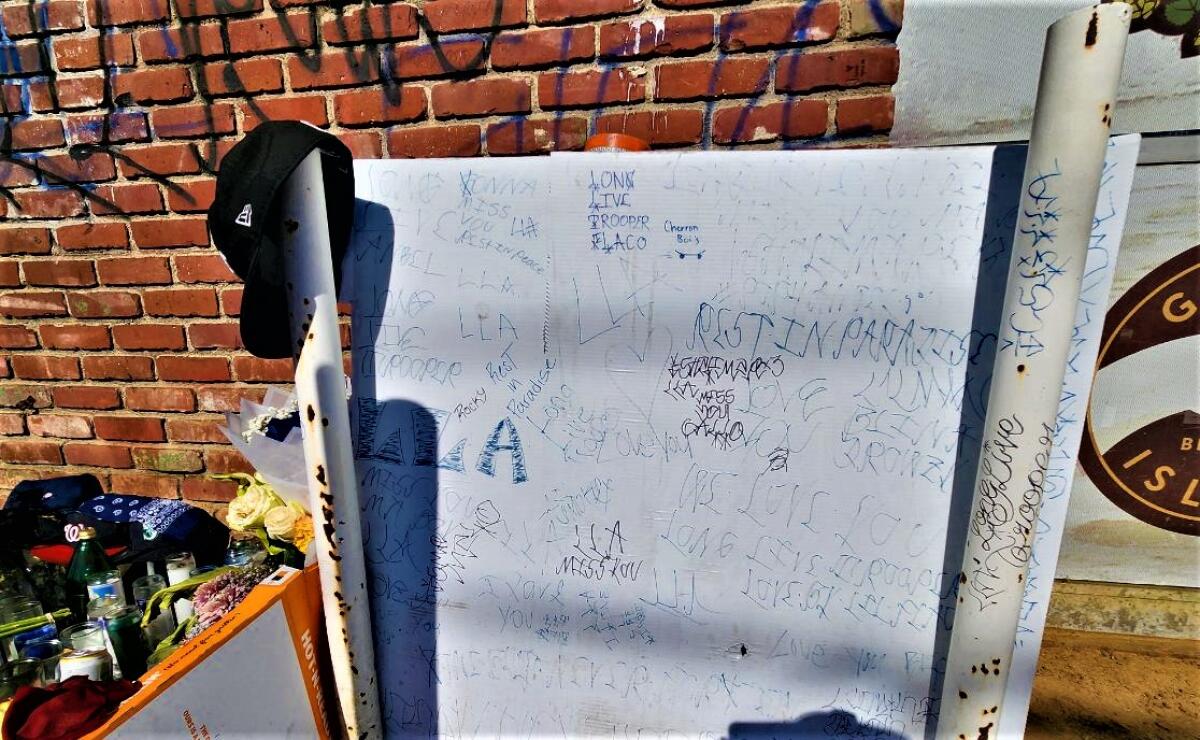 A board with writing on it pays tribute to a man killed in a stabbing outside a business. 