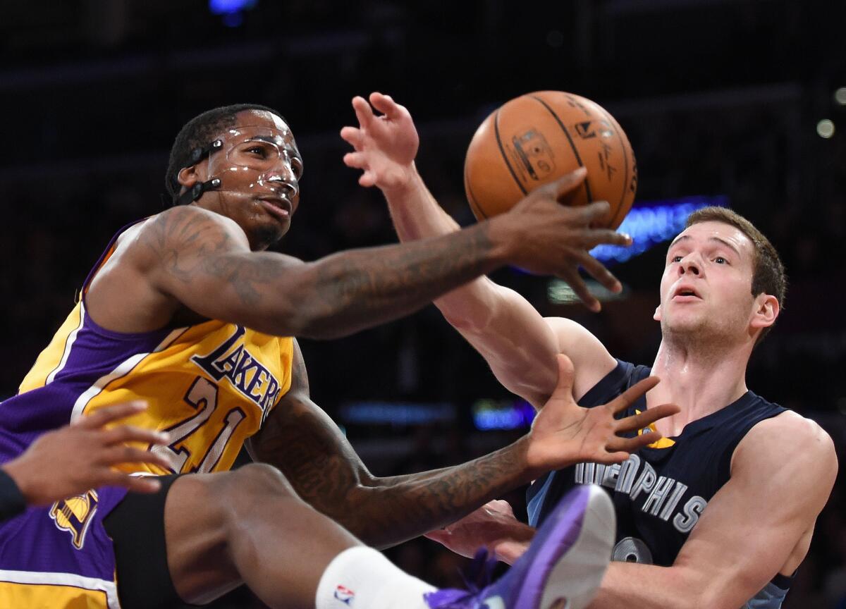 The Lakers' Ed Davis, fitted with a facemask after breaking his nose, grabs a rebound in front of Memphis forward Jon Leuer during the Lakers' 109-106 loss to the Grizzlies on Friday at Staples Center.