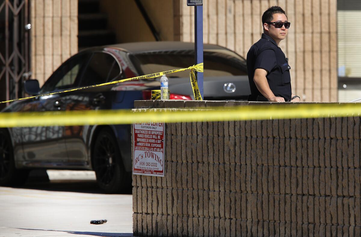 A Los Angeles police officer stands guard next to a semiautomatic handgun that was fired multiple times through the front windshield at officers in an LAPD SUV squad car in Reseda.