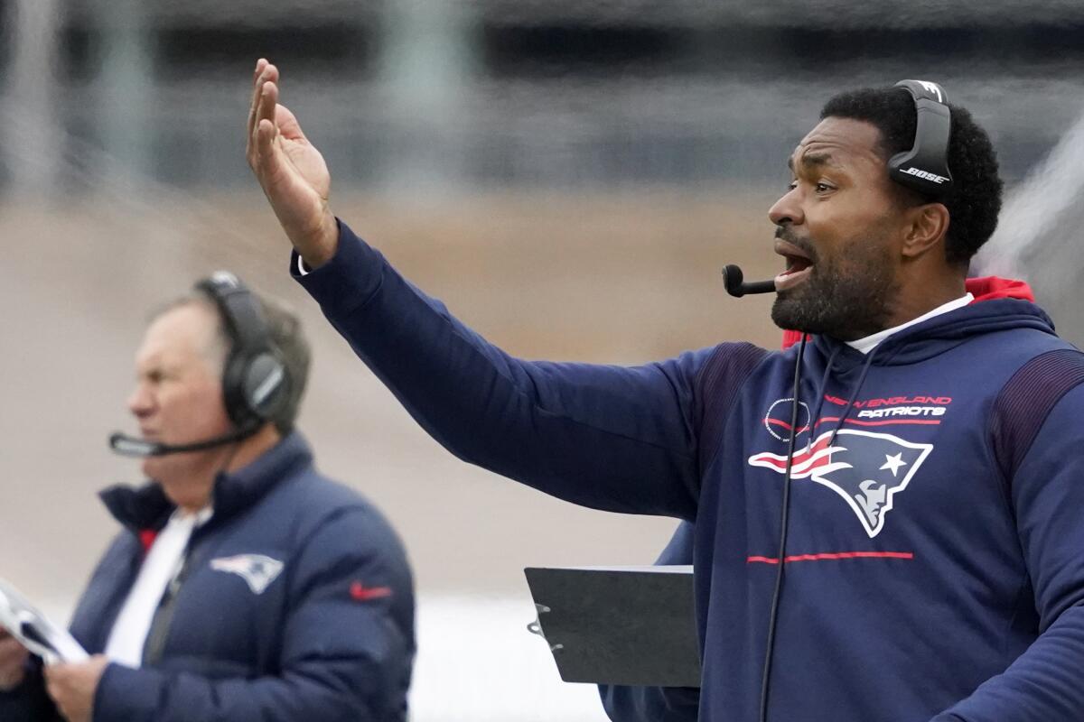 Patriots linebackers coach Jerod Mayo gestures on the sideline during a game. Coach Bill Belichick is in the background.