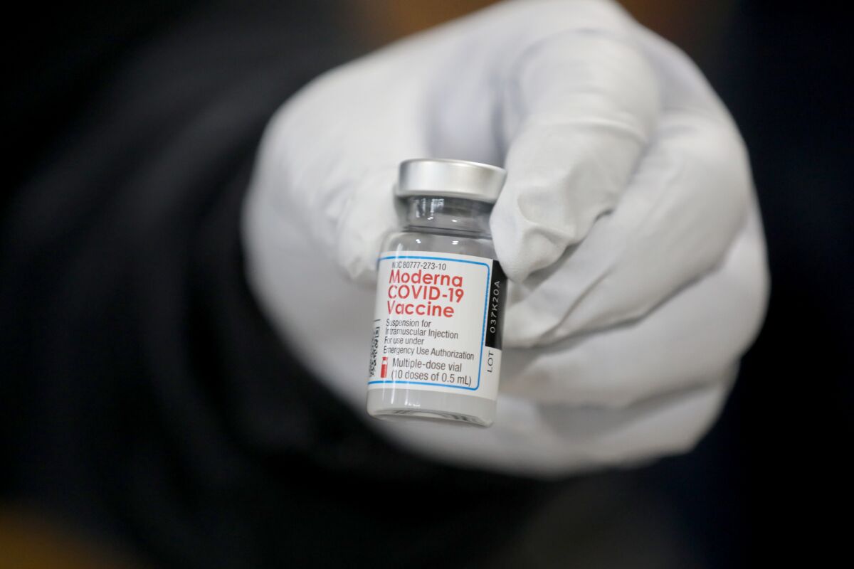 A Los Angeles Fire Department paramedic holds a vial of Moderna's COVID-19 vaccine.