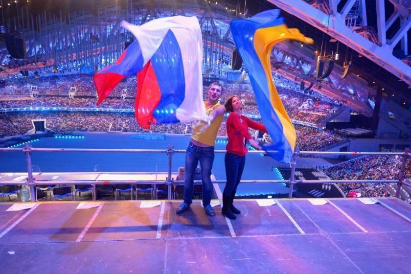 Spectators wave Russian and Ukrainian flags ahead of the opening ceremony of the Sochi Paralympic Games.
