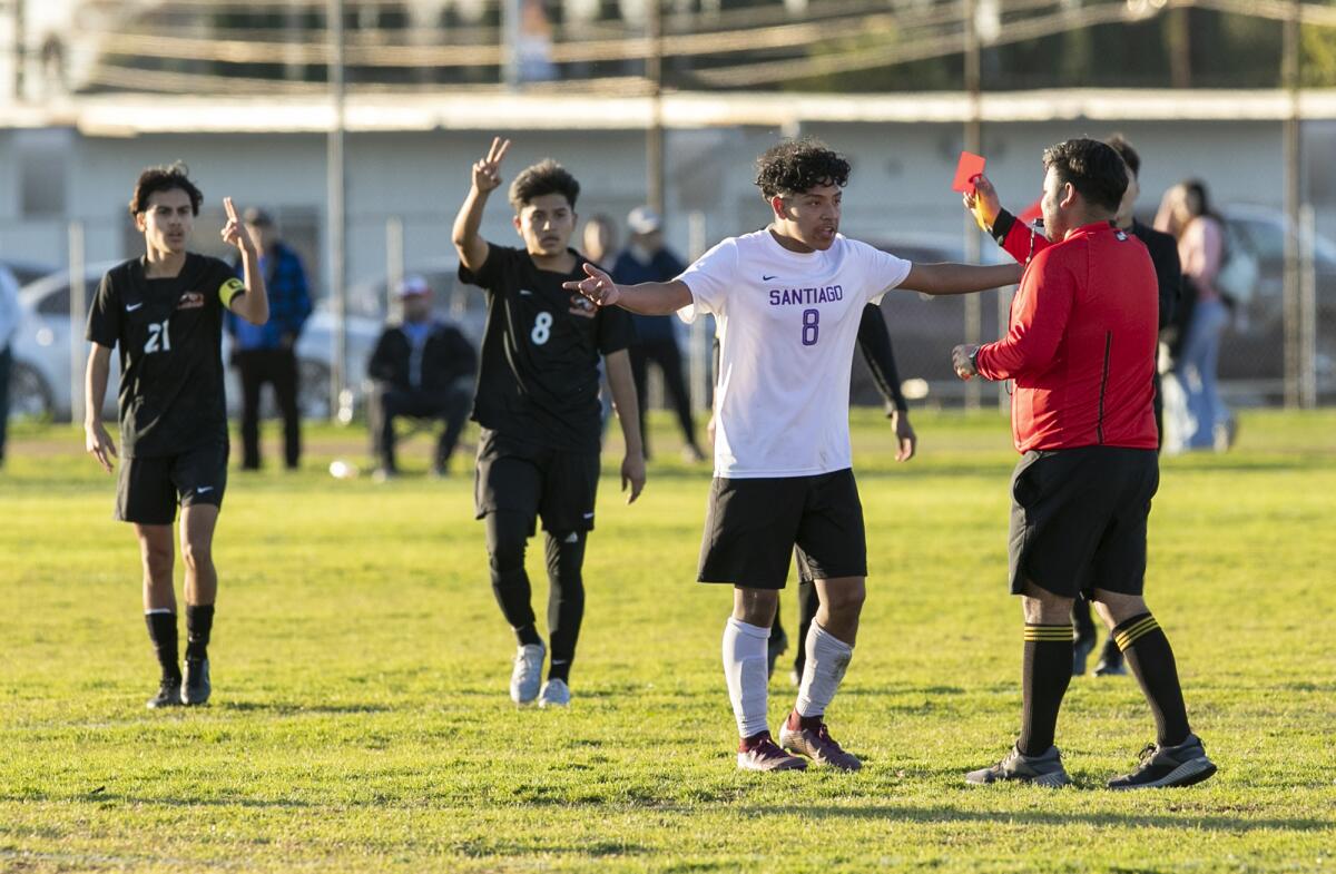 The referee gives a red card to Santiago's Roger Cruz during a Garden Grove League match on Tuesday.