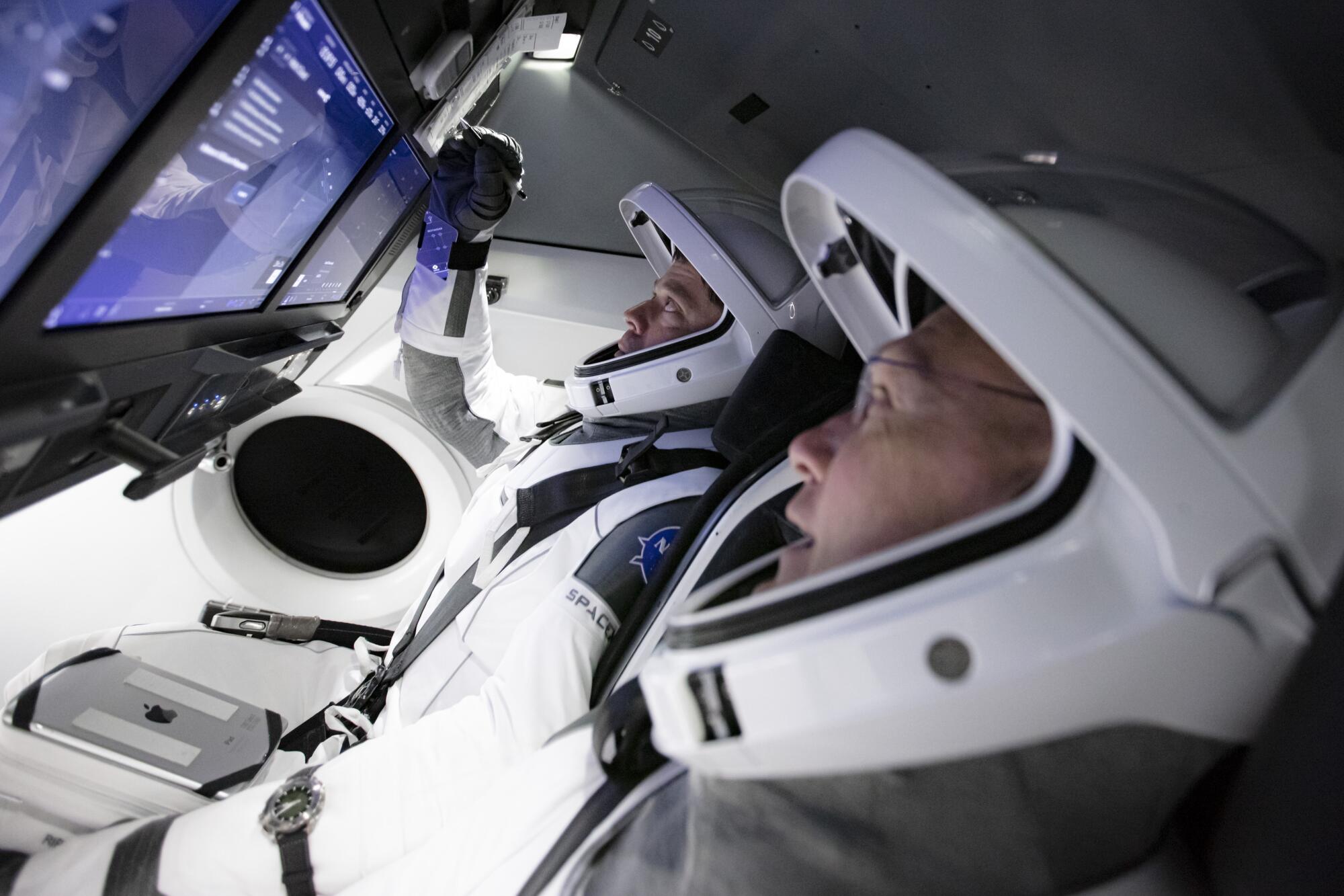 Astronauts Doug Hurley, foreground, and Bob Behnken work in SpaceX's flight simulator at the Kennedy Space Center in Cape Canaveral, Fla., in March.