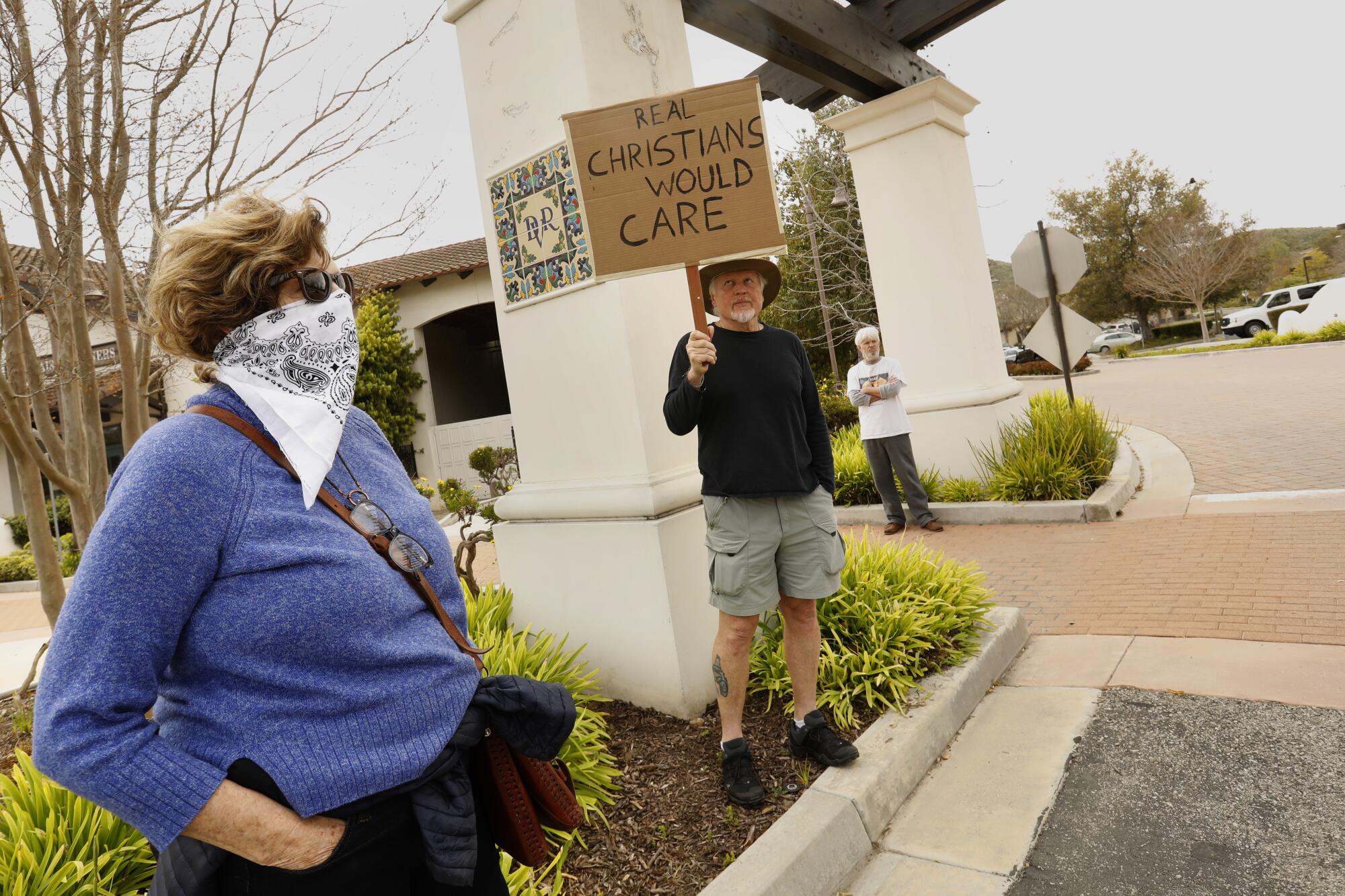 About 20 people, including Catherine Saillant, left, protested outside Godspeak Calvary Chapel in opposition to Communion being given inside.