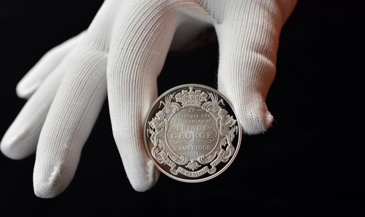 In this undated photo released Tuesday, Oct. 8, 2013, by Solent for the British Royal Mint, a 5 pound (with a face value of $8) silver coin produced to commemorate the upcoming christening of Prince George of Cambridge is displayed.